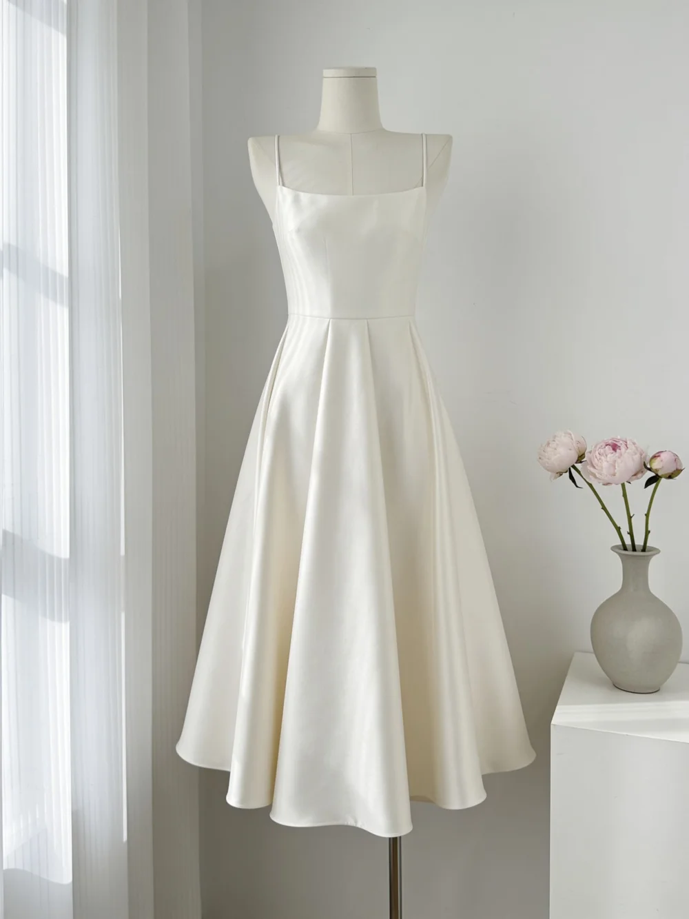 AI product shot example: ivory satin slip dress on a dress form, bright indoor scene